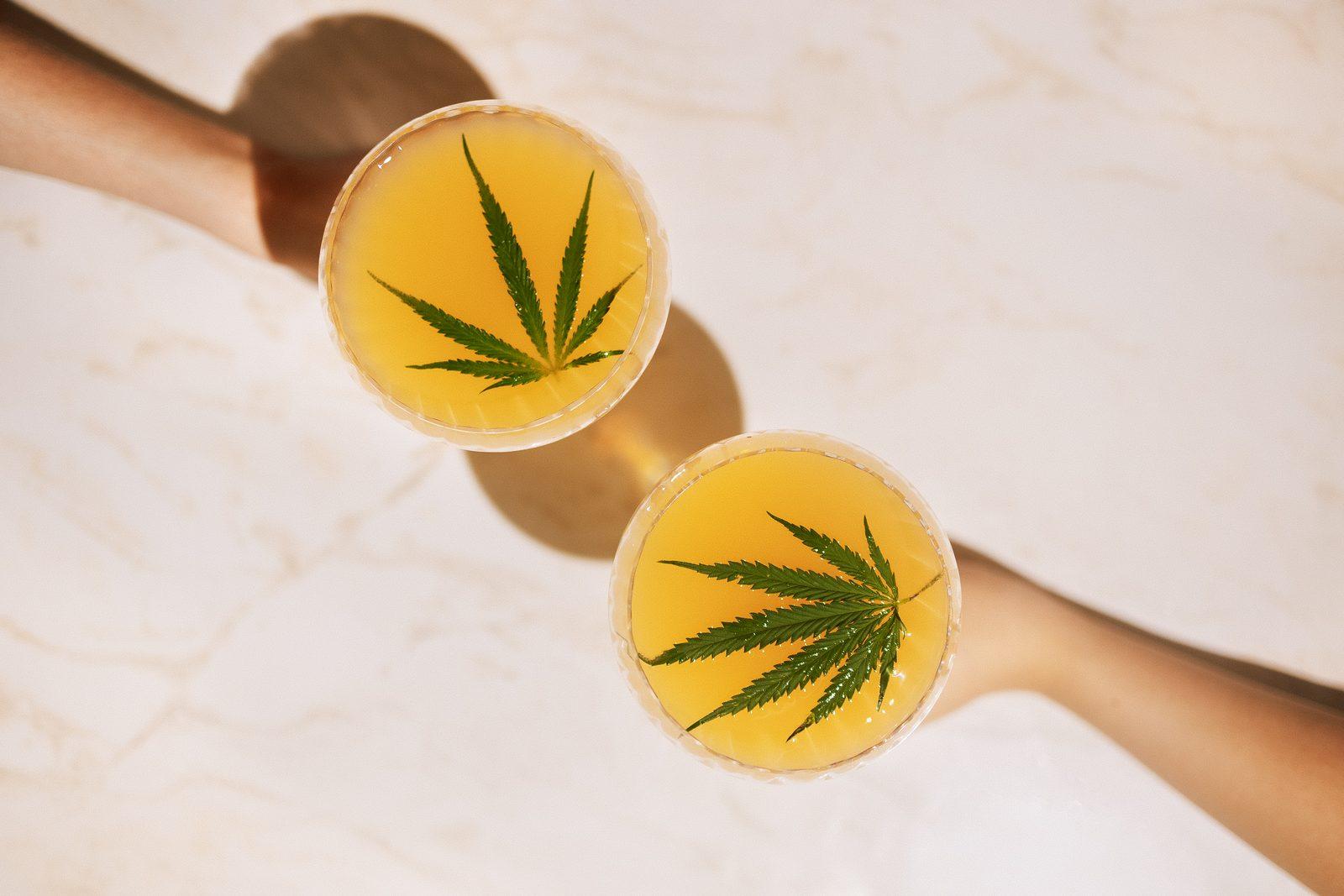 Sparkling beverages with cannabis leaves on table