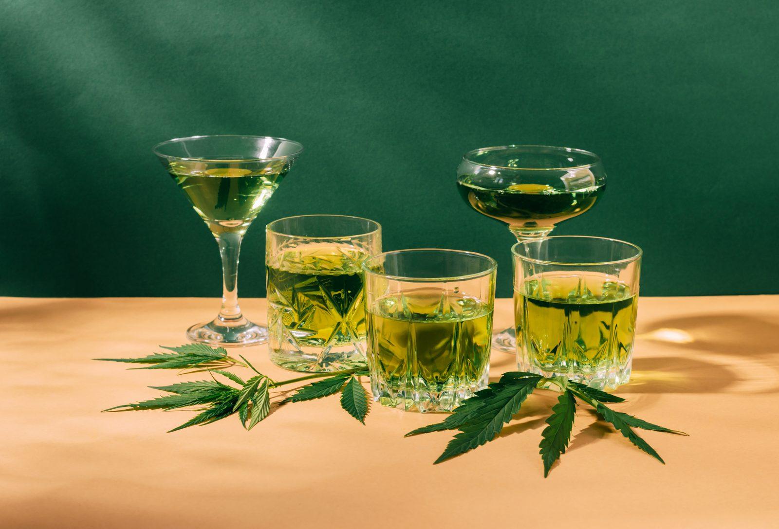 Green drinks and cannabis leaves on table